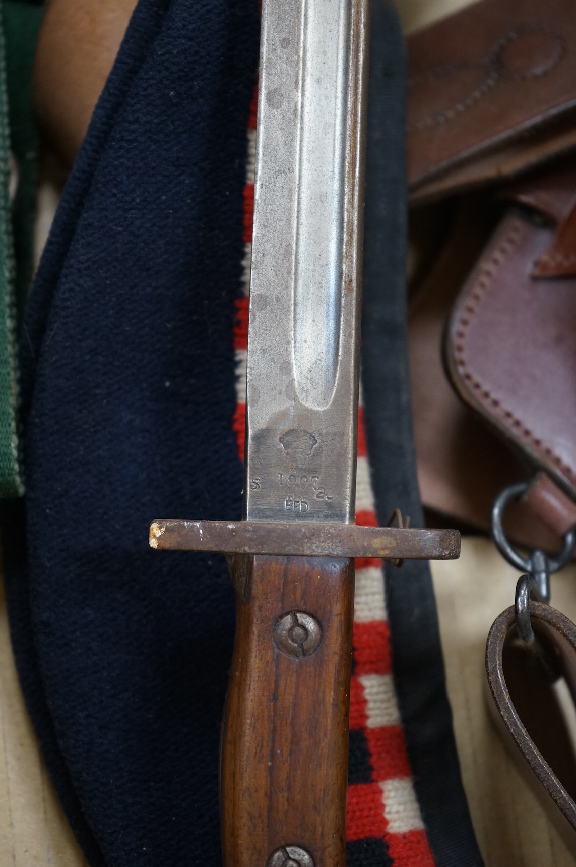 A 1907 bayonet in its scabbard with the tip of the blade shortened, together with a Glengarry cap of the KOSB, post 1902 badge and a brown leather shoulder belt and pouch with QE2 bronze badge of the Royal Artillery